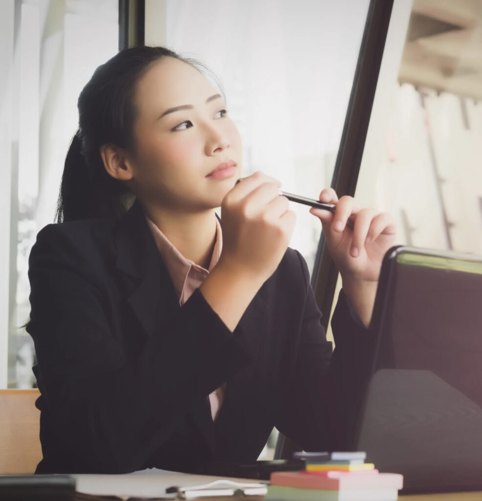 Businesswoman holding pen and thinking